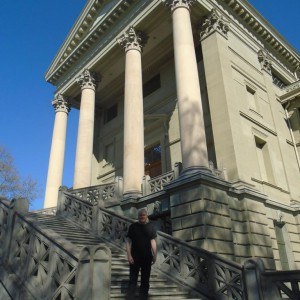 Colin Matthews standing on the steps of Stadthaus Winterthur (temple-like building with four pillars)