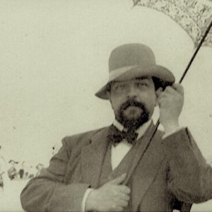 Black and white image of Debussy holding a parasol on a beach