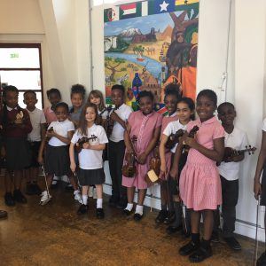 Colin Matthews with a group of 14 primary school children, all holding violins