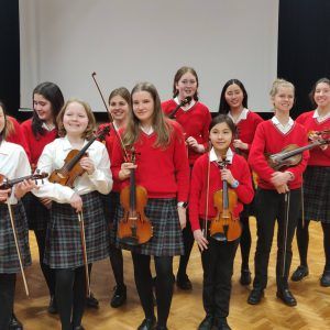 Group of young violinists in a concert hall with colin matthews and James Wilson