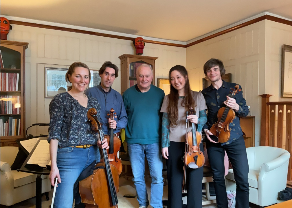 A string quartet standing together holding their instruments, with Colin 