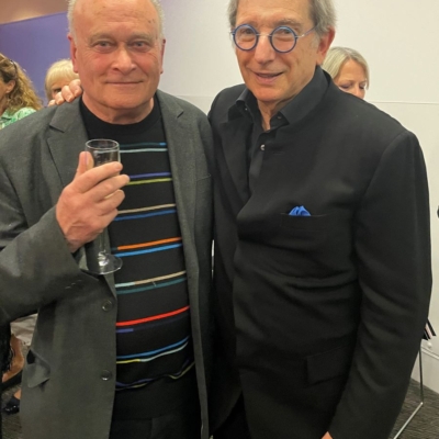 Colin Matthews and Michael Tilson Thomas stand smiling together at a gathering, Colin is holding a glass of wine