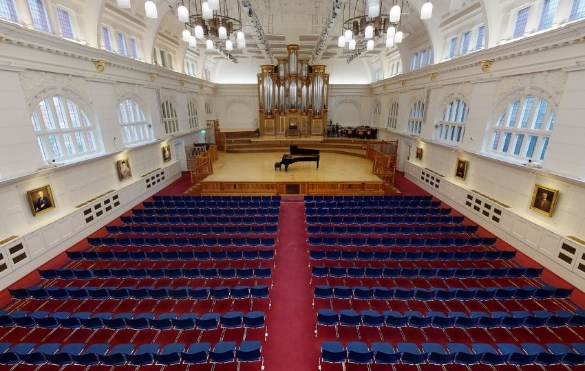 An empty concert hall with a grand piano on the stage
